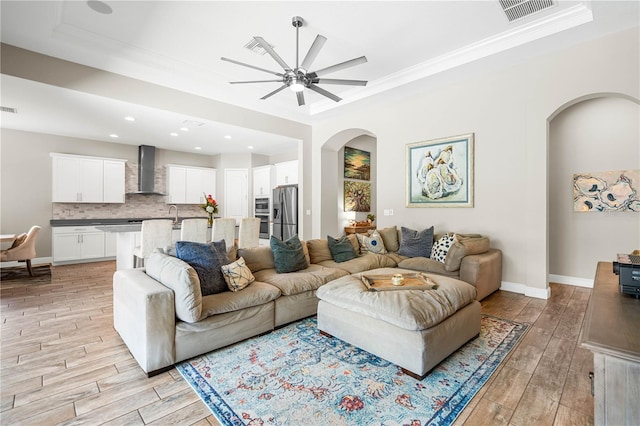 living room with ceiling fan, crown molding, and light wood-type flooring