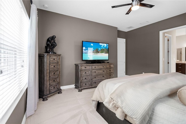 carpeted bedroom with ensuite bath and ceiling fan