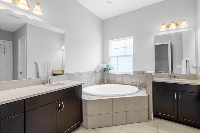 bathroom with tile patterned flooring, vanity, and a relaxing tiled tub