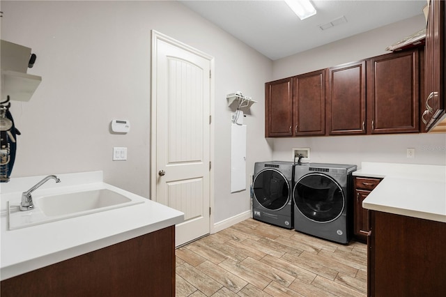 laundry area featuring cabinets, washing machine and clothes dryer, and sink