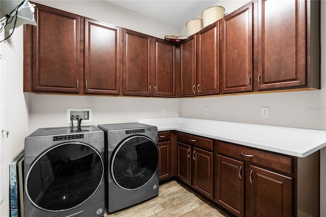 clothes washing area with cabinets and washing machine and dryer