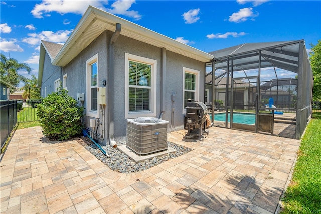 rear view of house featuring central AC, a fenced in pool, glass enclosure, and a patio area