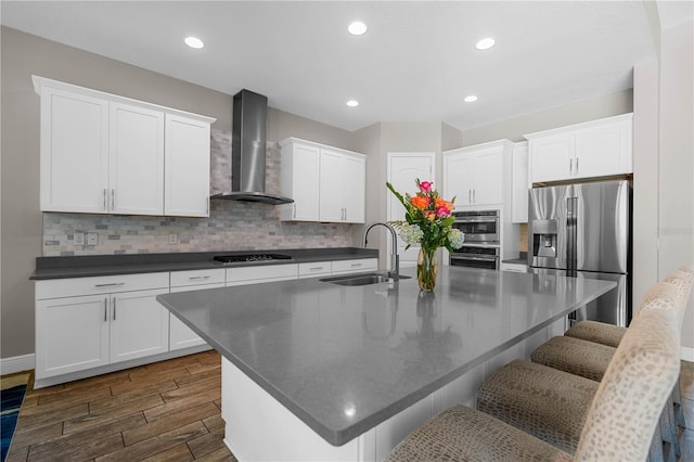 kitchen with white cabinets, stainless steel appliances, and wall chimney range hood