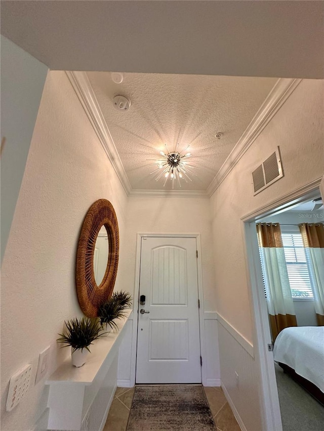 doorway featuring tile patterned floors, crown molding, and a textured ceiling