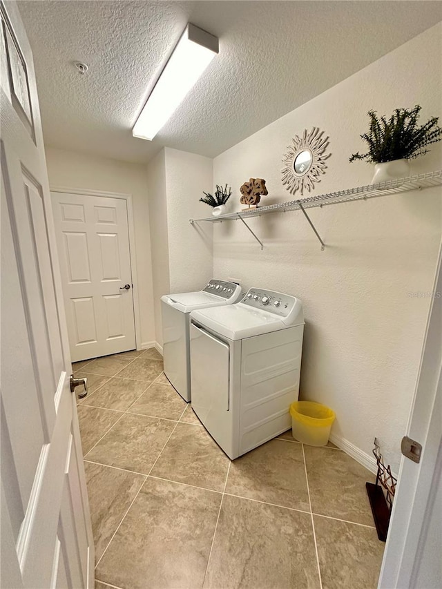 washroom featuring independent washer and dryer, a textured ceiling, and light tile patterned flooring