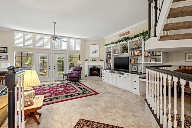 living room featuring a high ceiling, ceiling fan, and ornamental molding