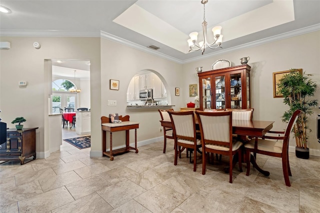 dining area with a chandelier, ornamental molding, and a tray ceiling