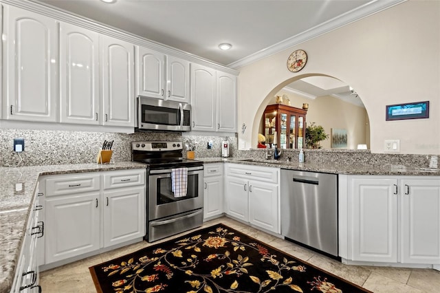 kitchen with decorative backsplash, light stone counters, white cabinetry, and appliances with stainless steel finishes