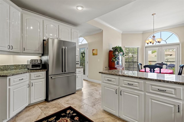 kitchen with white cabinets, an inviting chandelier, stainless steel refrigerator, and dark stone counters