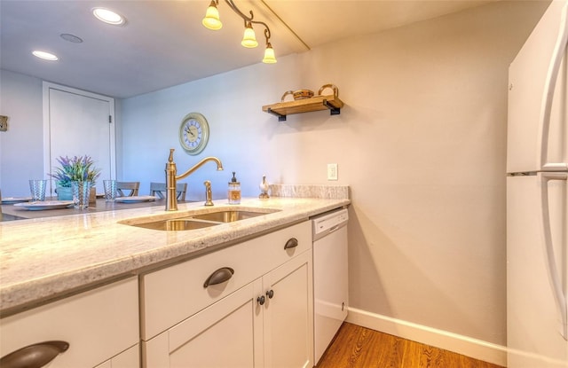 kitchen with white appliances, sink, light stone countertops, dark hardwood / wood-style flooring, and white cabinetry