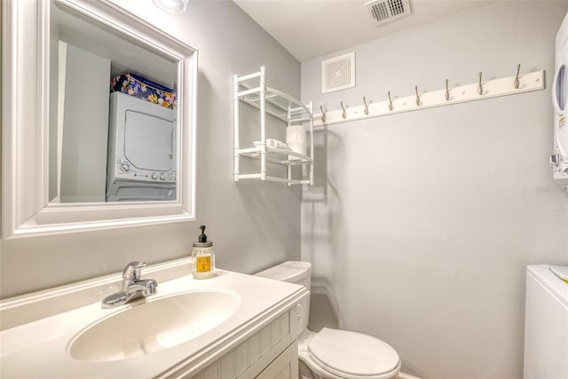 bathroom featuring vanity, stacked washer / drying machine, and toilet