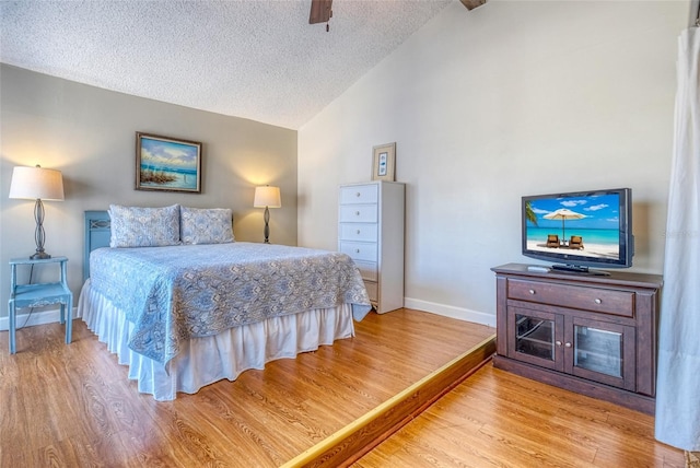 bedroom featuring ceiling fan, lofted ceiling with beams, light hardwood / wood-style floors, and a textured ceiling