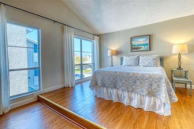 bedroom featuring lofted ceiling, a textured ceiling, and light hardwood / wood-style flooring