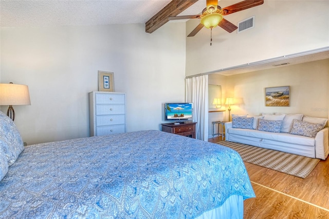 bedroom with vaulted ceiling with beams, ceiling fan, a textured ceiling, and hardwood / wood-style flooring