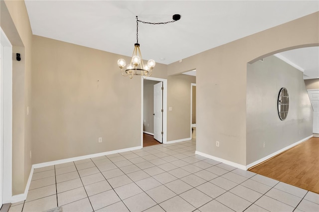 empty room with light tile patterned floors and a chandelier