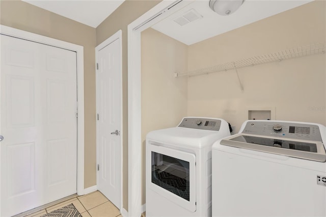 laundry area with independent washer and dryer and light tile patterned flooring