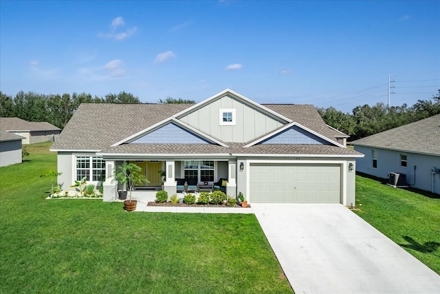 craftsman-style home featuring concrete driveway, a front yard, a garage, a shingled roof, and covered porch