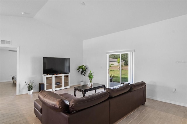 living room featuring high vaulted ceiling and light hardwood / wood-style flooring