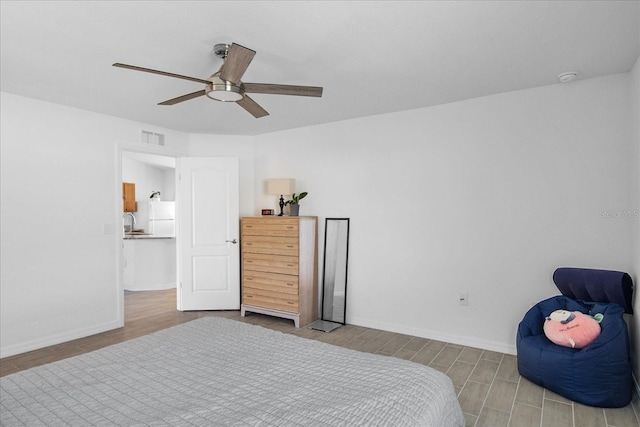 bedroom featuring ceiling fan, light wood-type flooring, and white fridge