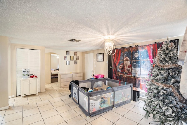 rec room with light tile patterned floors, a textured ceiling, and a notable chandelier