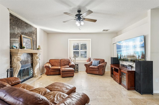 living room featuring a fireplace, a textured ceiling, and ceiling fan