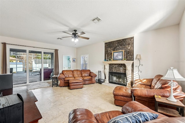 living room with a fireplace, a textured ceiling, and ceiling fan