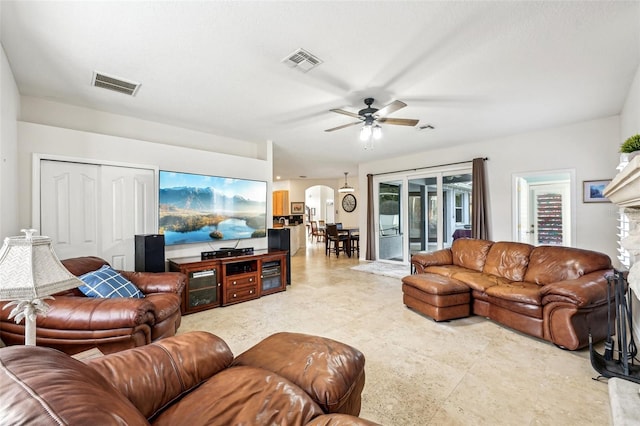 living room featuring ceiling fan and a stone fireplace