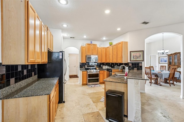 kitchen with kitchen peninsula, appliances with stainless steel finishes, backsplash, sink, and hanging light fixtures