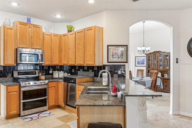 kitchen with sink, hanging light fixtures, stainless steel appliances, kitchen peninsula, and a chandelier