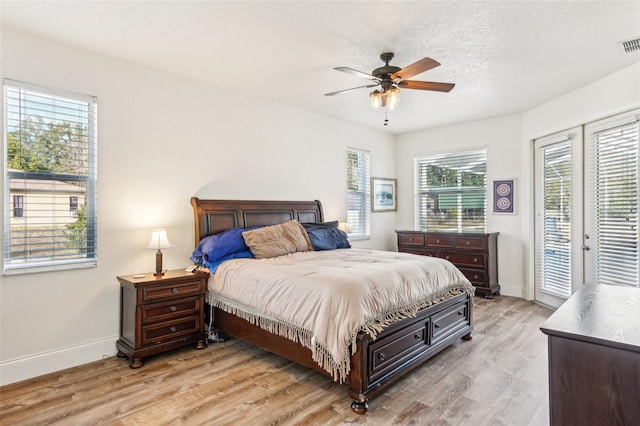 bedroom featuring access to exterior, ceiling fan, light hardwood / wood-style floors, and multiple windows