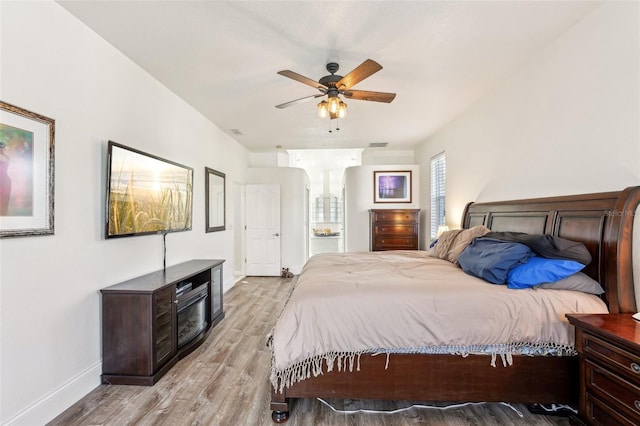 bedroom with ceiling fan, connected bathroom, and light hardwood / wood-style flooring