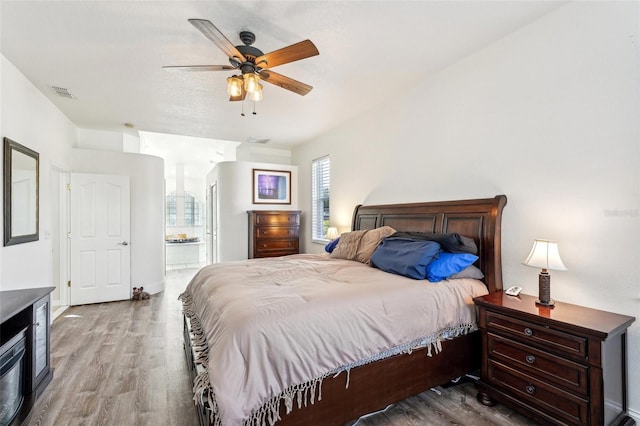 bedroom with ensuite bath, ceiling fan, and hardwood / wood-style floors