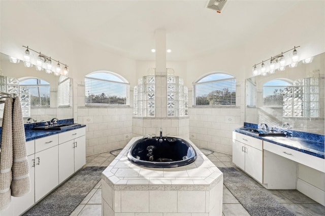 bathroom with tile patterned flooring, tile walls, a wealth of natural light, and tiled bath