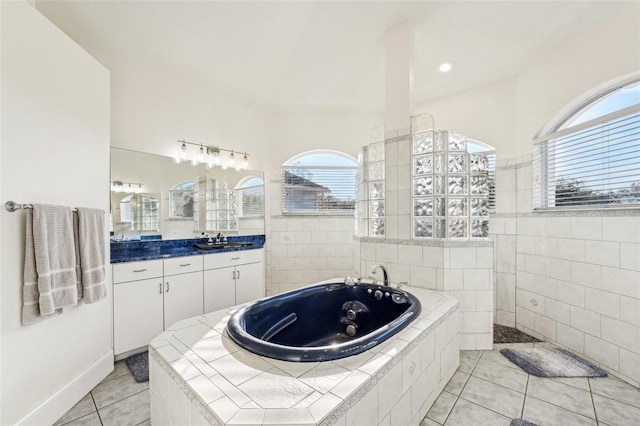 bathroom with tile patterned flooring, vanity, and a relaxing tiled tub