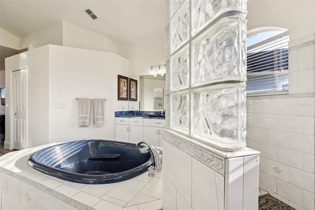 bathroom featuring tiled bath, vanity, and lofted ceiling