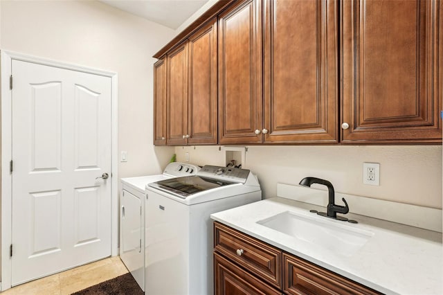 laundry area with cabinets, light tile patterned floors, washer and dryer, and sink