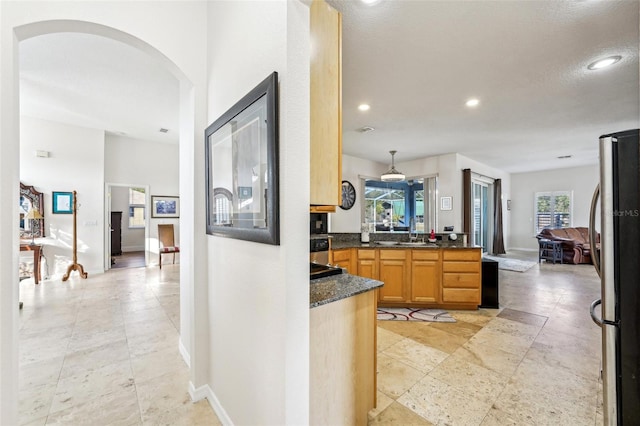 kitchen featuring stainless steel fridge, decorative light fixtures, plenty of natural light, and sink