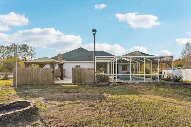 rear view of house with a lanai, a lawn, a gazebo, and a fenced in pool