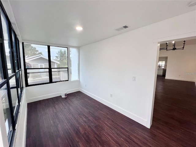 spare room featuring dark hardwood / wood-style floors and an inviting chandelier