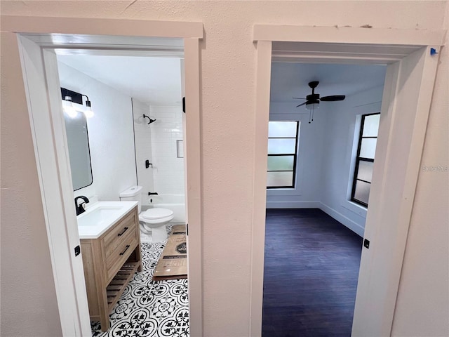 full bathroom with vanity, tiled shower / bath combo, ceiling fan, hardwood / wood-style flooring, and toilet