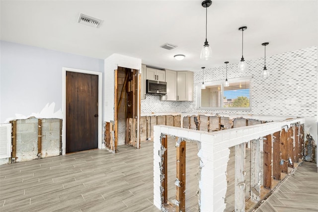 kitchen featuring a kitchen bar, decorative backsplash, hanging light fixtures, kitchen peninsula, and light hardwood / wood-style flooring