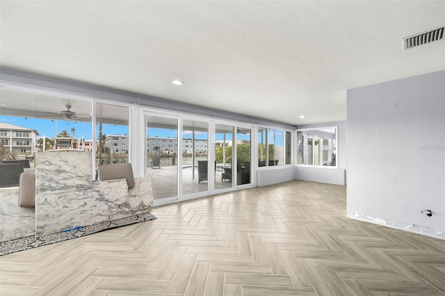 unfurnished living room with ceiling fan, a wealth of natural light, and light parquet flooring