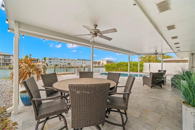 view of patio / terrace featuring a water view, ceiling fan, and a fenced in pool