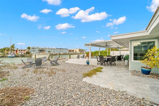 view of yard with ceiling fan, a patio area, and a water view