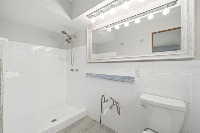 bathroom with tile walls, toilet, and tiled shower