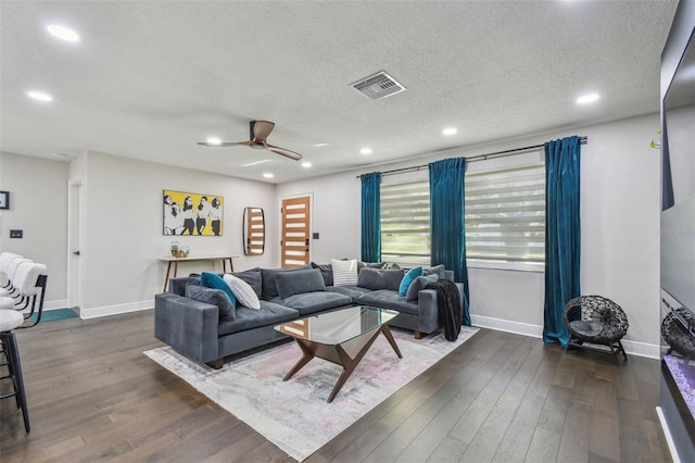 living room with ceiling fan, dark hardwood / wood-style flooring, and a textured ceiling