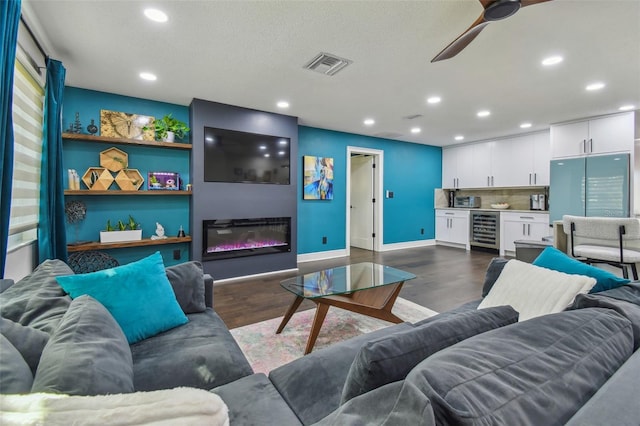 living room with a textured ceiling, ceiling fan, dark wood-type flooring, and beverage cooler