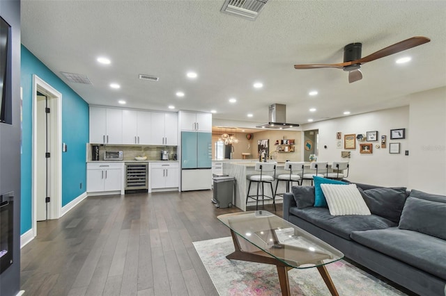 living room with a textured ceiling, ceiling fan, dark wood-type flooring, and beverage cooler