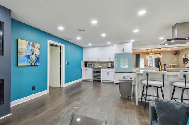 kitchen featuring wine cooler, kitchen peninsula, decorative light fixtures, a breakfast bar area, and white cabinets