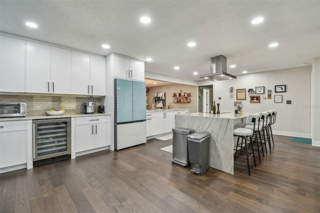 kitchen with wine cooler, island exhaust hood, white cabinets, and white refrigerator